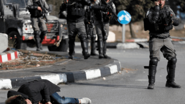 A Palestinian man lies on the ground after being shot by Israeli forces. Photo: Reuters