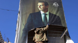 Un militante strappa uno striscione con l'immagine del presidente siriano Bashar al-Assad ad Aleppo il 30 novembre 2024. Foto: Mohammed Al-Rifai/AFP/Getty Images